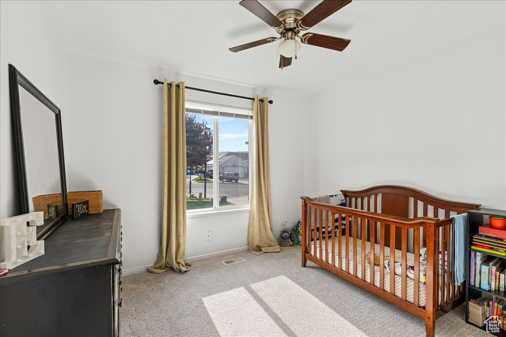 Bedroom with carpet flooring, a nursery area, and a ceiling fan