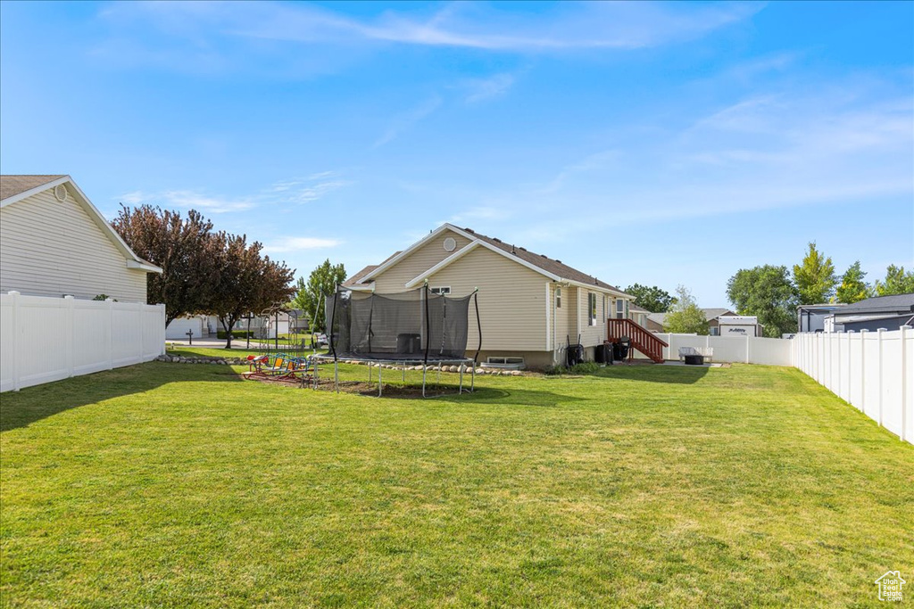 Fenced backyard featuring a trampoline