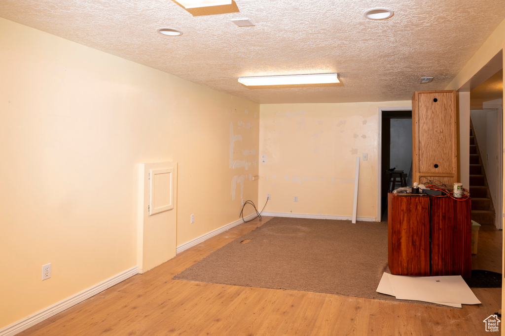 Unfurnished room featuring stairs, a textured ceiling, wood finished floors, and recessed lighting