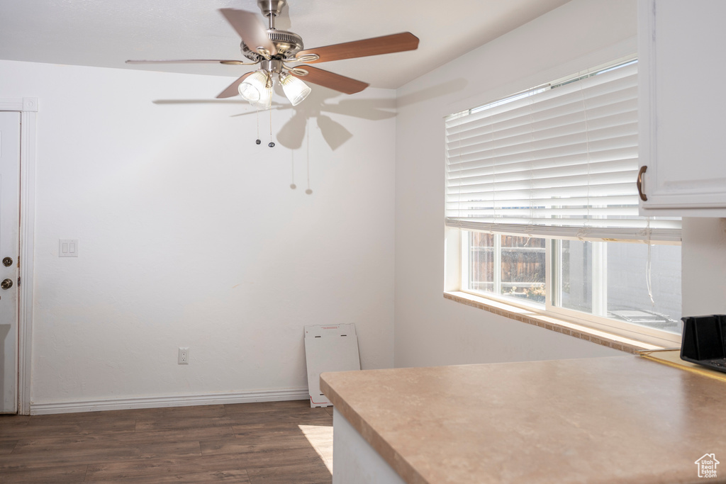 Unfurnished dining area featuring ceiling fan and dark wood-style floors