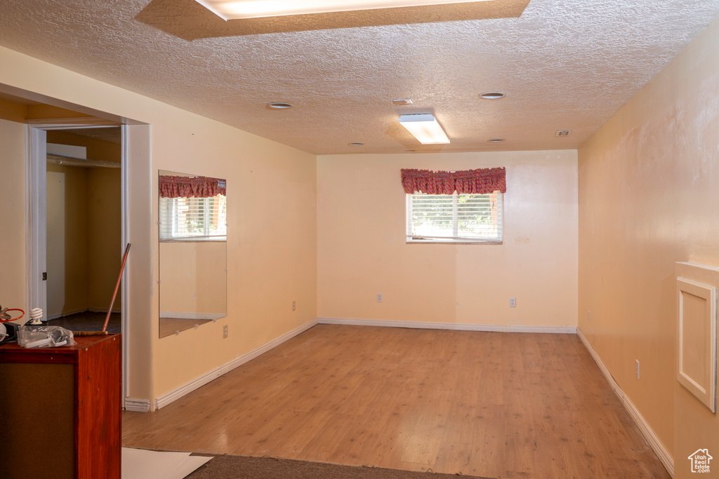 Unfurnished room with a textured ceiling, light wood-style floors, and plenty of natural light