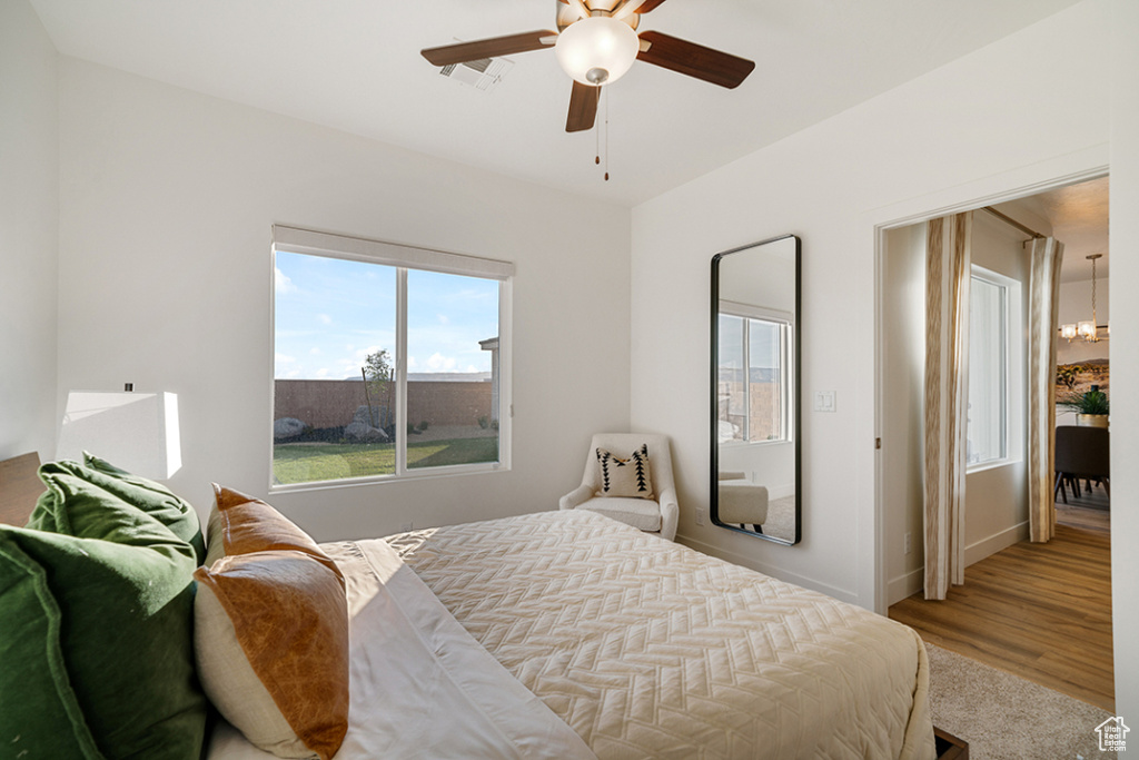 Bedroom with a chandelier, ceiling fan, and wood finished floors