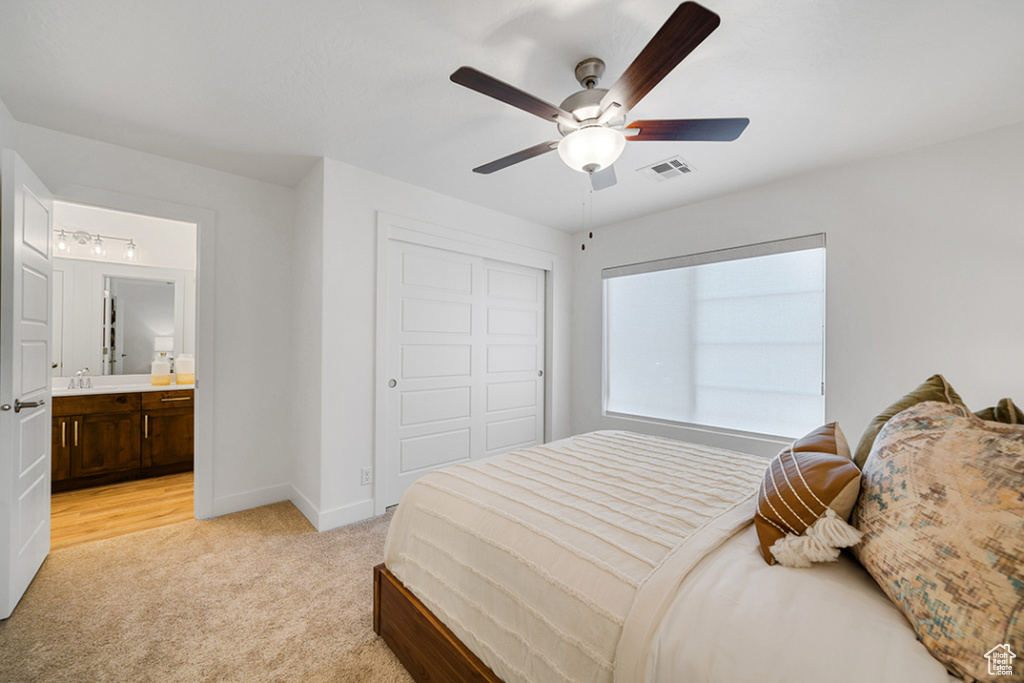 Bedroom featuring light carpet, a closet, ceiling fan, and ensuite bathroom