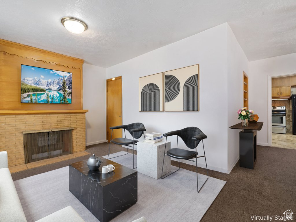 Living room featuring a fireplace, carpet flooring, and a textured ceiling