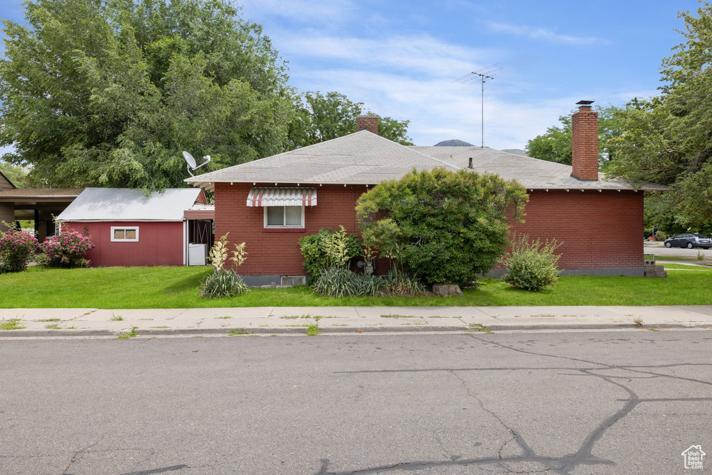 Single story home with a chimney and a front lawn