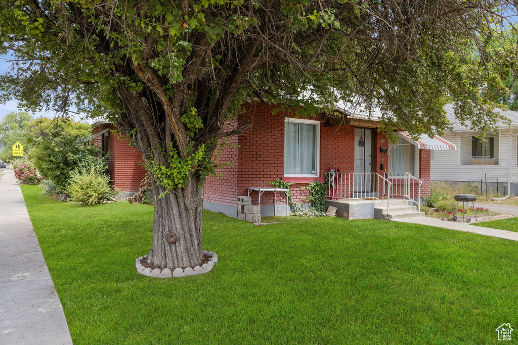 View of front of property with a front yard and brick siding
