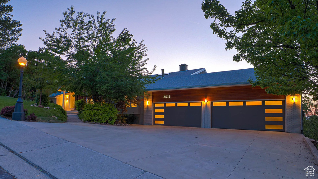 View of front of house with concrete driveway and a chimney