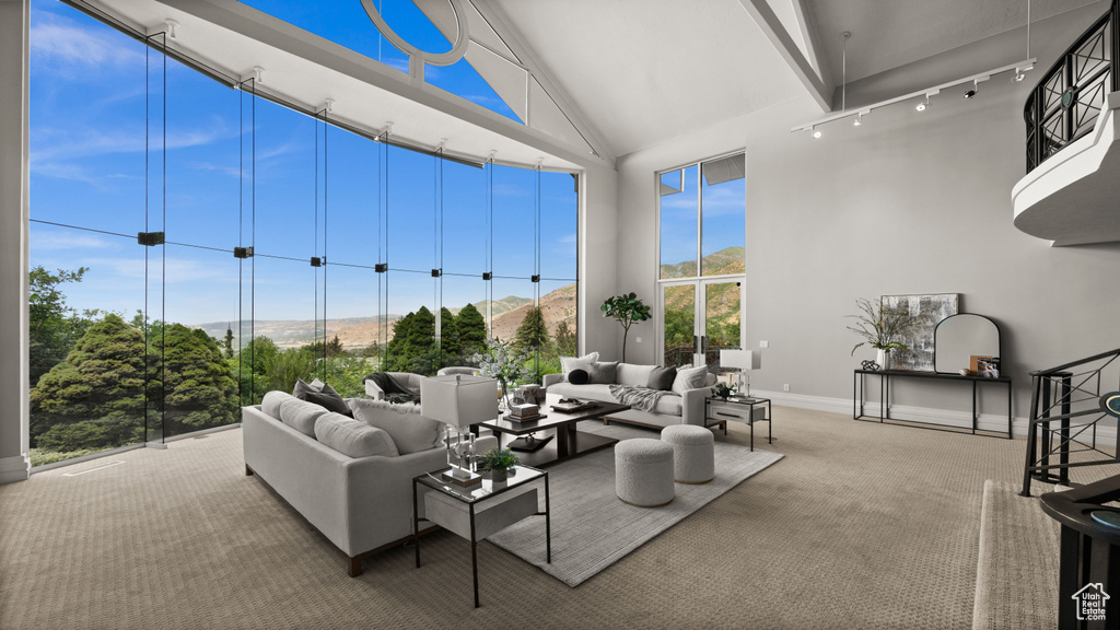 Living area featuring high vaulted ceiling, rail lighting, carpet flooring, and a mountain view