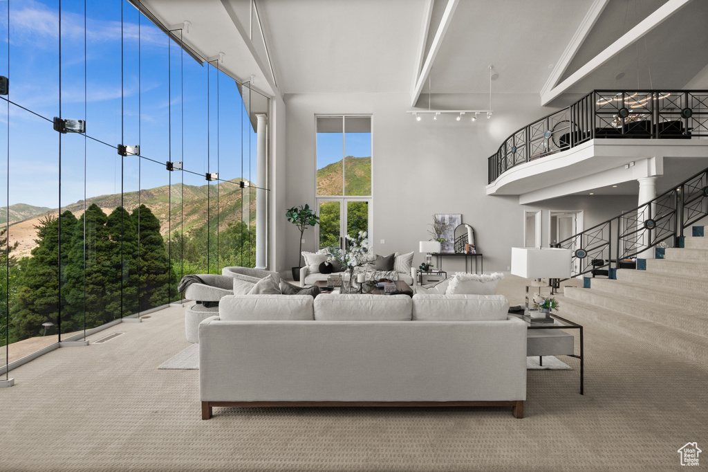 Carpeted living area with a towering ceiling, a mountain view, and stairway