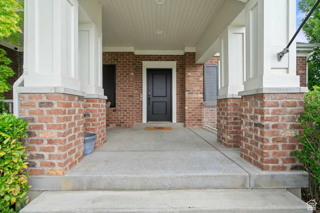 View of exterior entry with brick siding and a porch