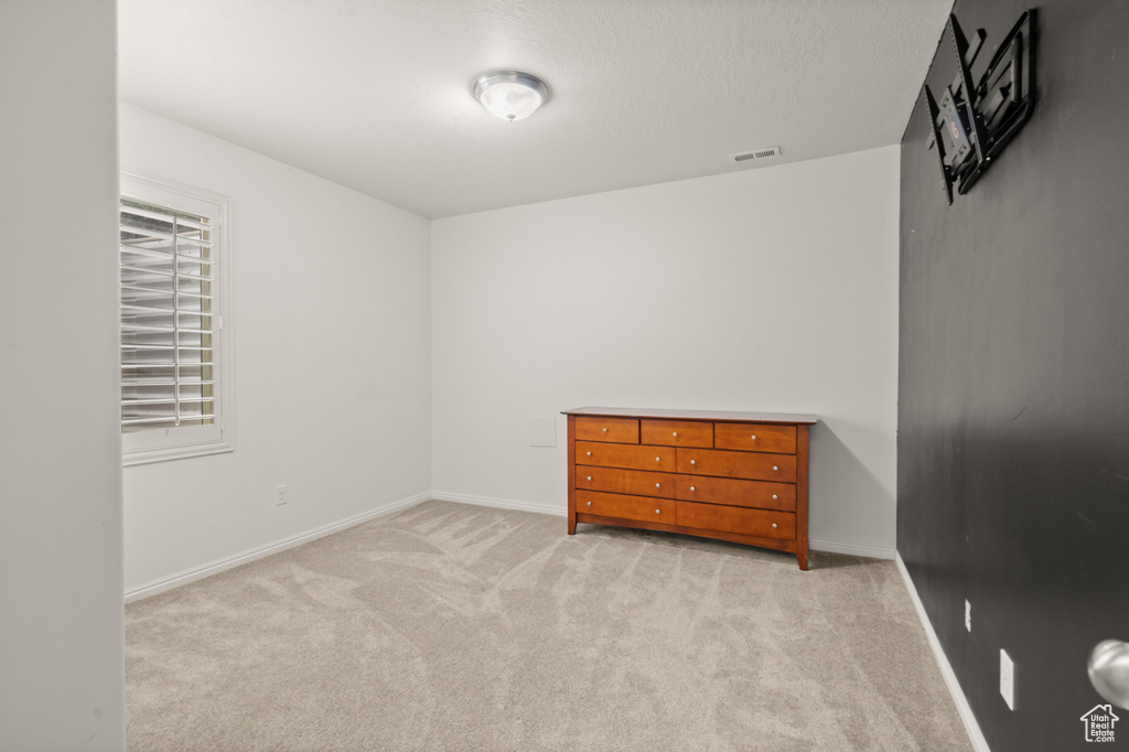 Unfurnished bedroom featuring light carpet and baseboards