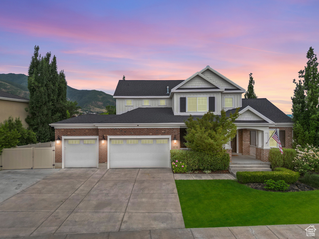View of front of home featuring driveway, a garage, brick siding, and a gate