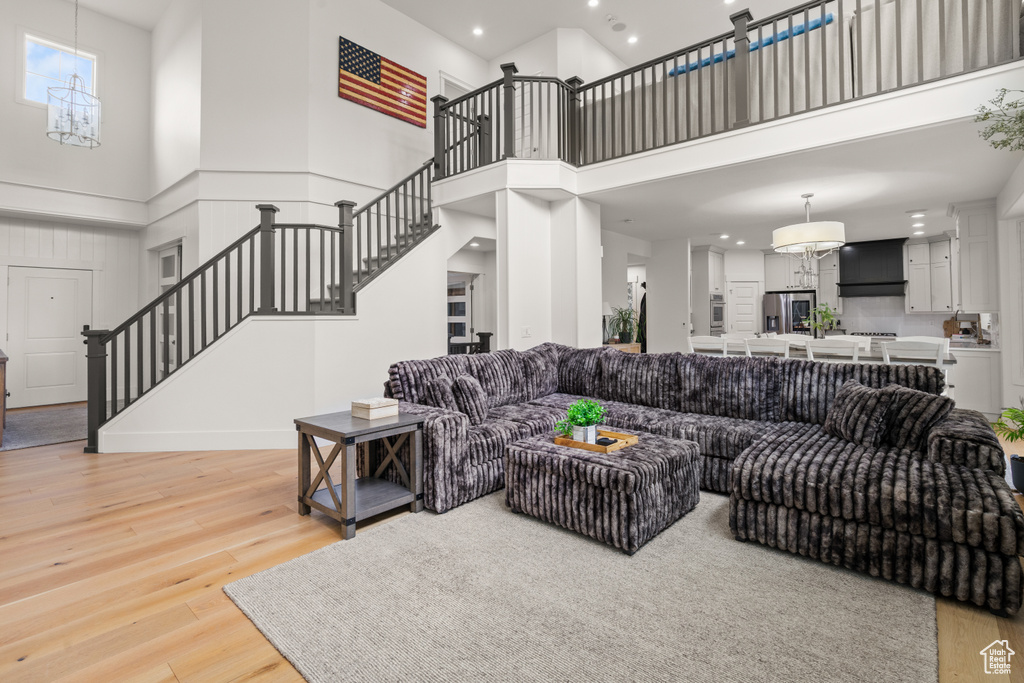 Living area with a chandelier, stairway, a high ceiling, recessed lighting, and light wood-type flooring