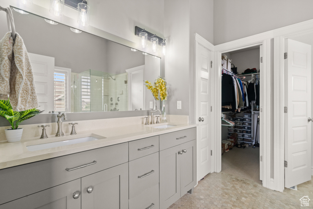Bathroom with a shower stall, double vanity, and a walk in closet