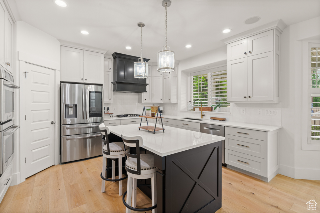 Kitchen with stainless steel appliances, backsplash, light wood-style flooring, light countertops, and recessed lighting