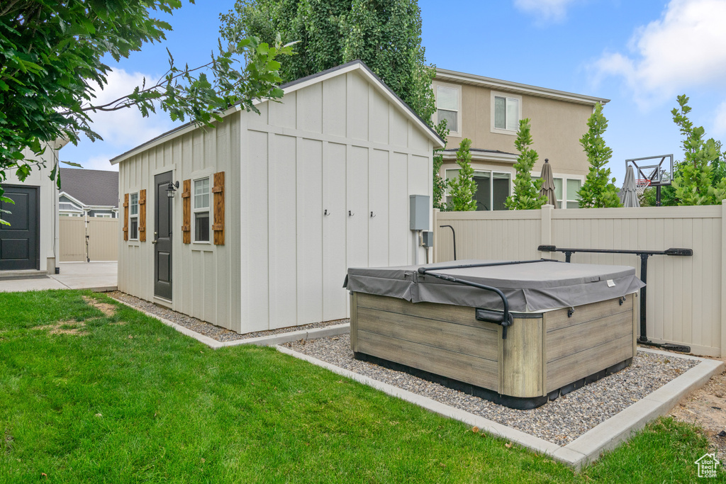 Back of property with a hot tub, board and batten siding, and a storage shed