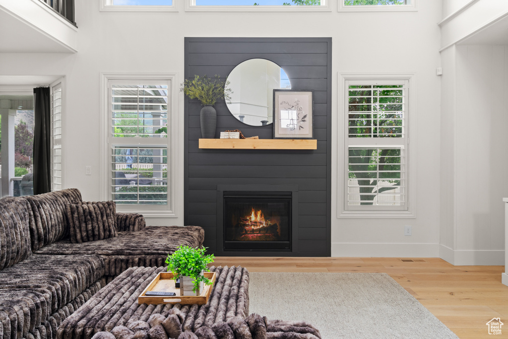 Living room with wood finished floors, healthy amount of natural light, a fireplace, and a high ceiling