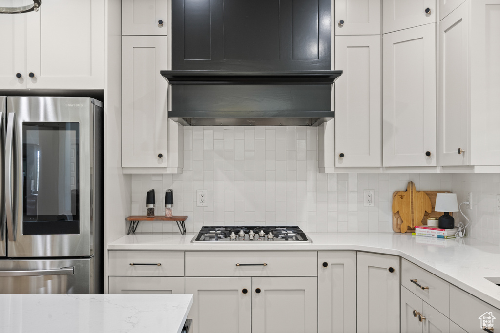 Kitchen featuring smart refrigerator, stainless steel gas stovetop, tasteful backsplash, and white cabinets