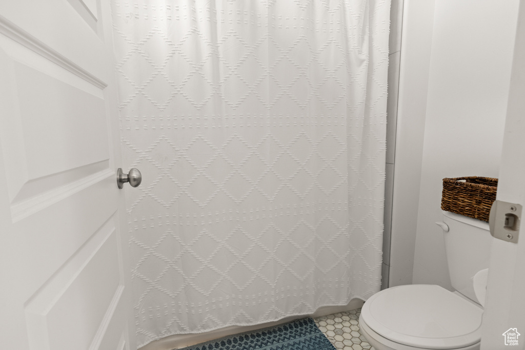 Bathroom featuring toilet and curtained shower