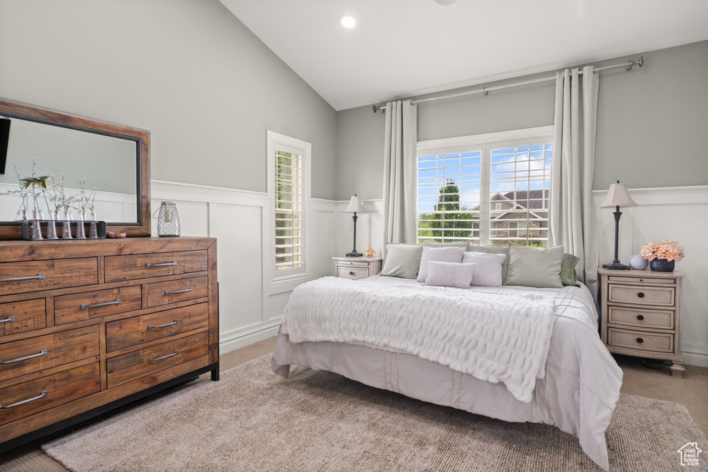 Carpeted bedroom featuring wainscoting, high vaulted ceiling, a decorative wall, and recessed lighting