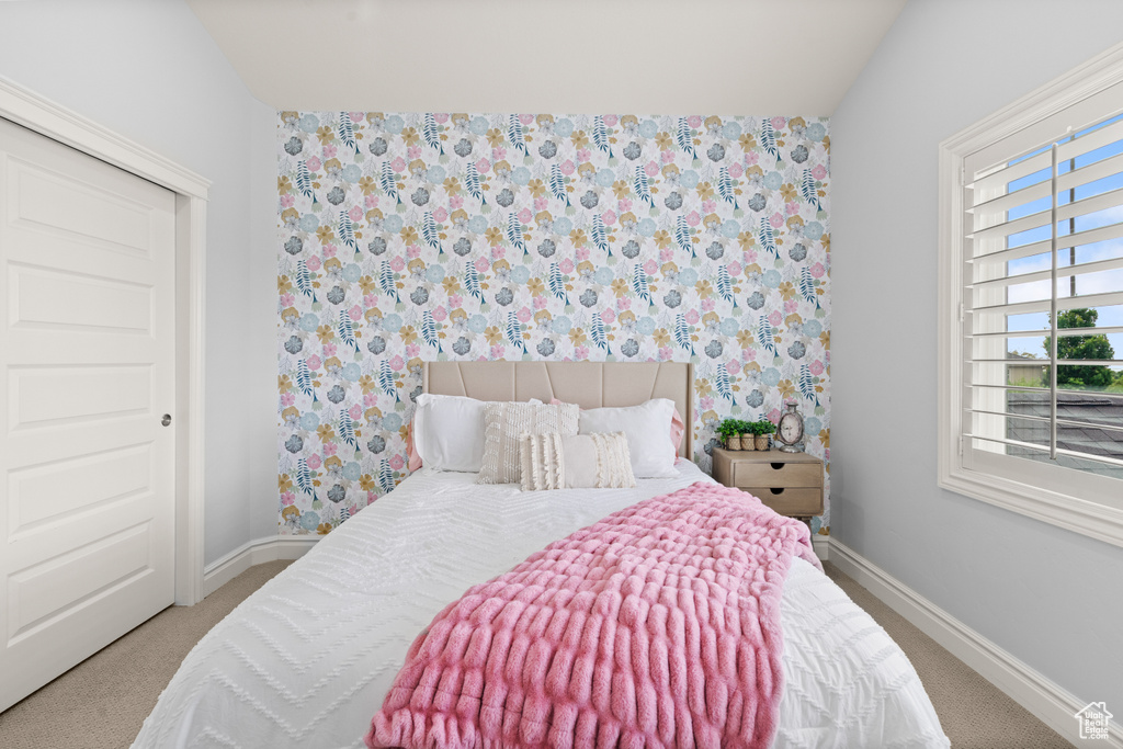 Carpeted bedroom with wallpapered walls and vaulted ceiling