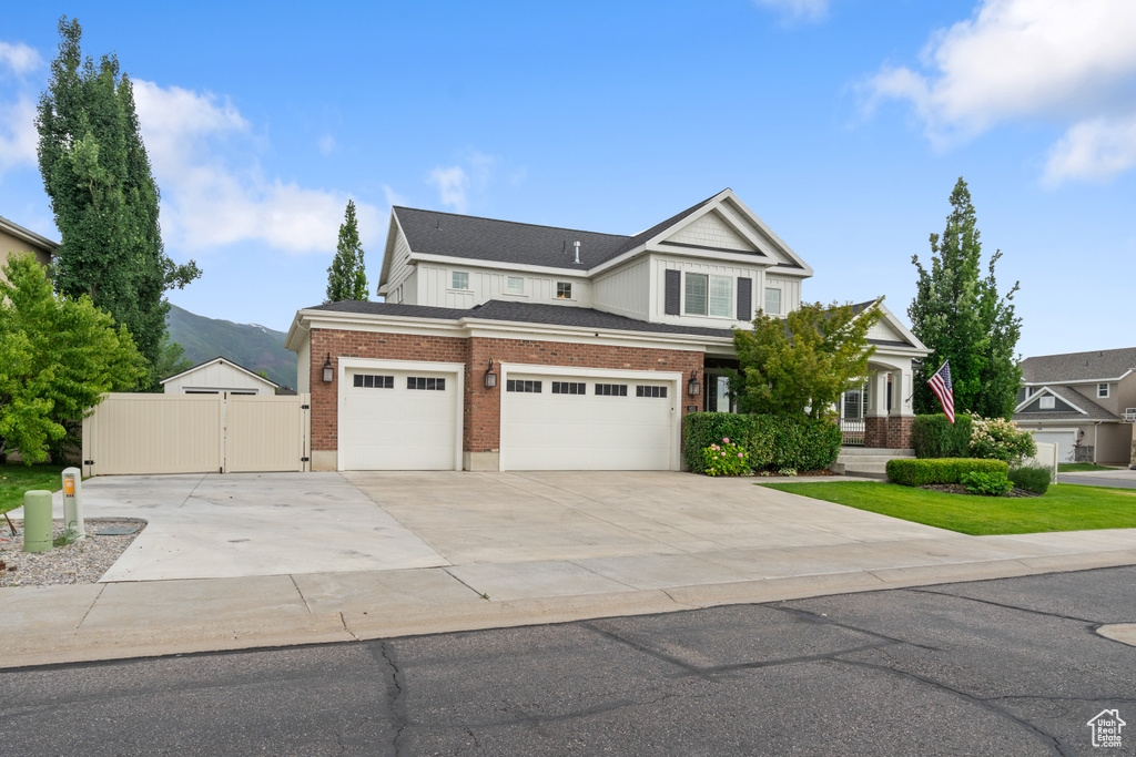 View of front of home with a gate, concrete driveway, brick siding, a mountain view, and a garage