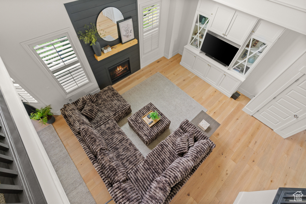 Living area with light wood finished floors, a large fireplace, and healthy amount of natural light
