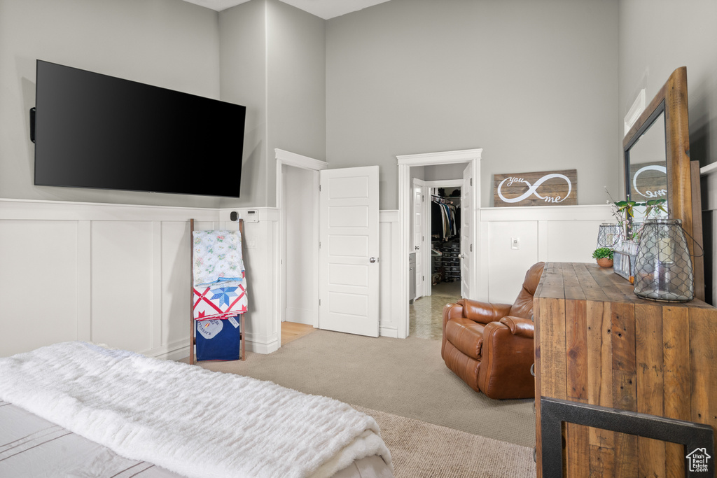 Bedroom featuring carpet, a walk in closet, a closet, wainscoting, and a decorative wall