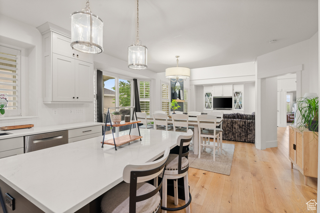 Kitchen featuring light countertops, light wood-style floors, pendant lighting, and white cabinets