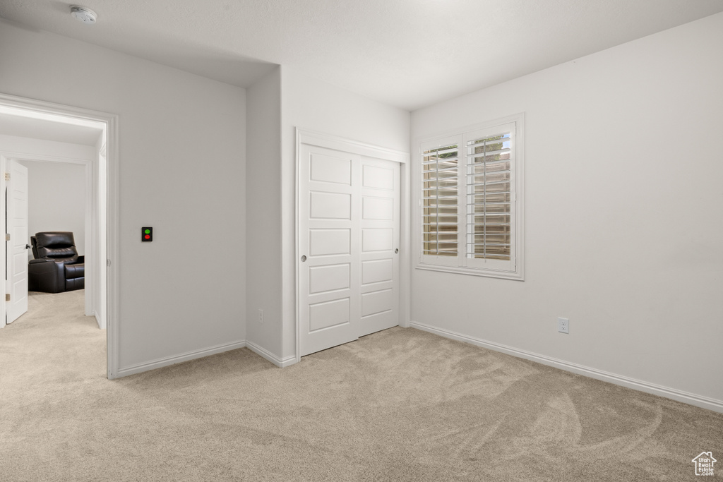 Unfurnished bedroom with light colored carpet and a closet