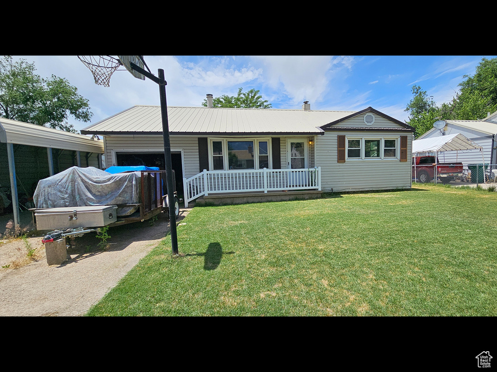 Ranch-style house with a garage, covered porch, a front yard, a metal roof, and driveway