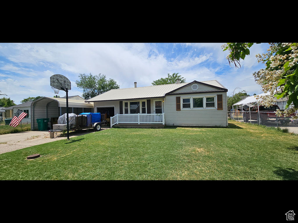View of front of house with covered porch, an attached garage, a metal roof, and a detached carport