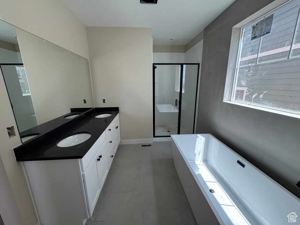 Bathroom featuring a tub to relax in, double vanity, a stall shower, and tile patterned flooring