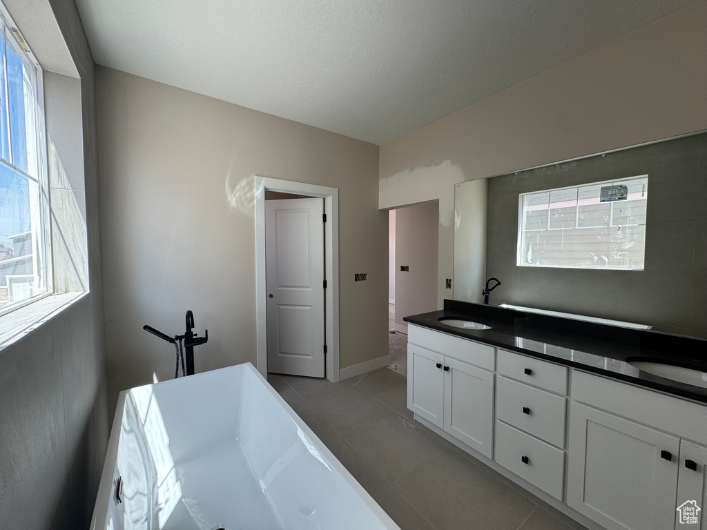 Full bath featuring a freestanding bath, tile patterned floors, and double vanity