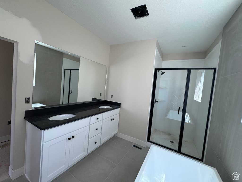 Bathroom featuring double vanity, a stall shower, a textured ceiling, and tile patterned flooring