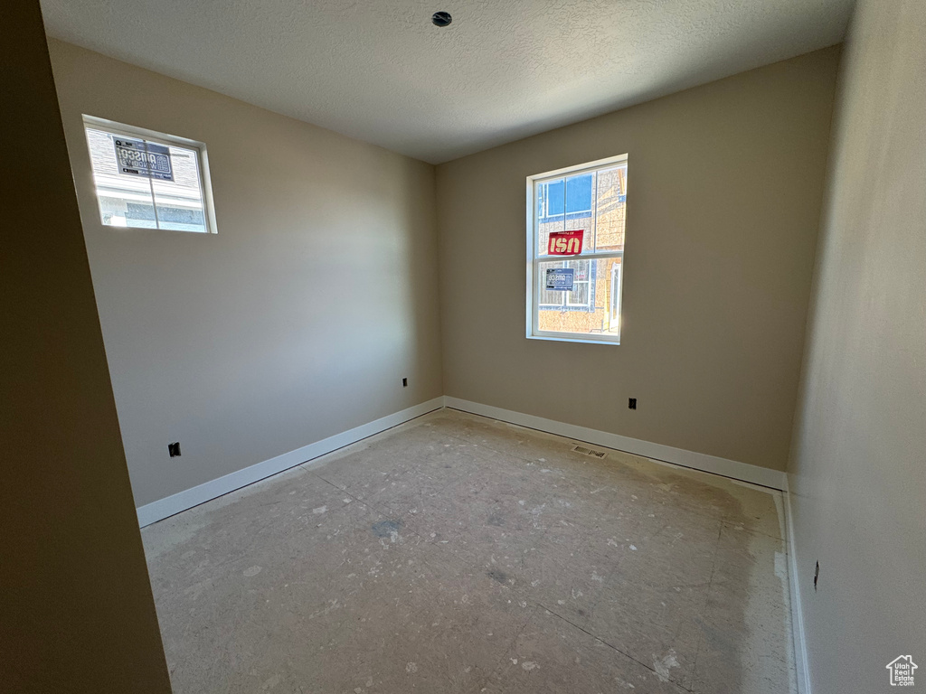Empty room with plenty of natural light and a textured ceiling