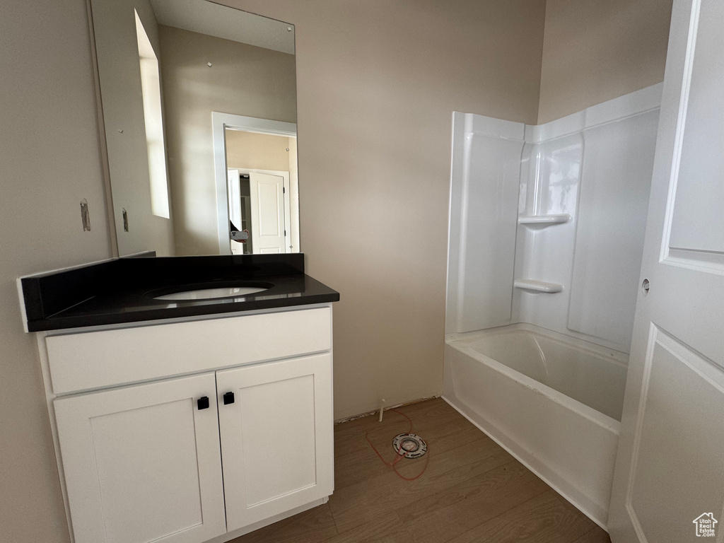 Full bath with wood finished floors, vanity, and shower / washtub combination