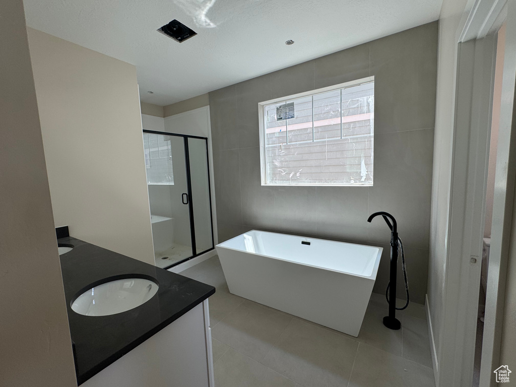 Full bathroom with double vanity, a stall shower, a freestanding tub, and tile patterned floors
