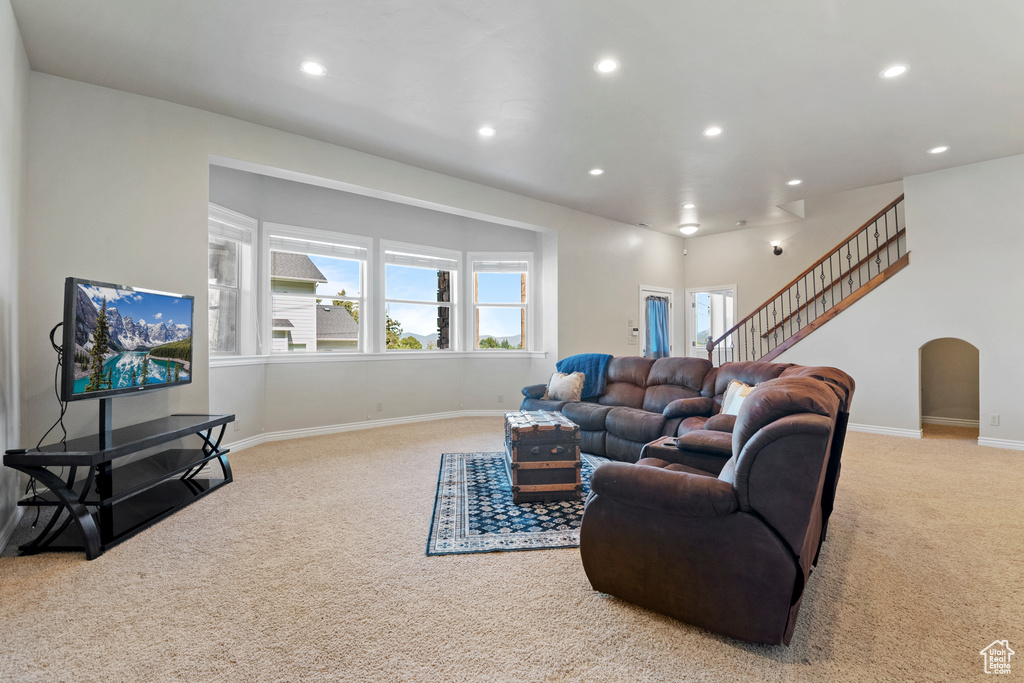Carpeted living room with recessed lighting, arched walkways, and stairs