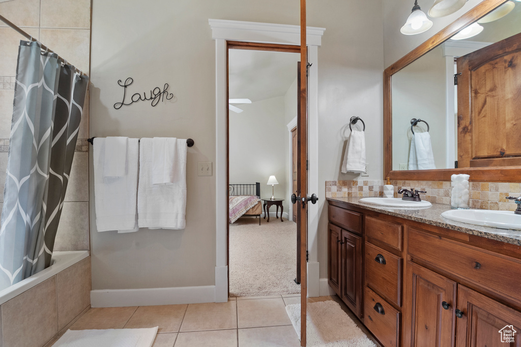 Ensuite bathroom featuring double vanity, tile patterned flooring, backsplash, and tiled shower / bath