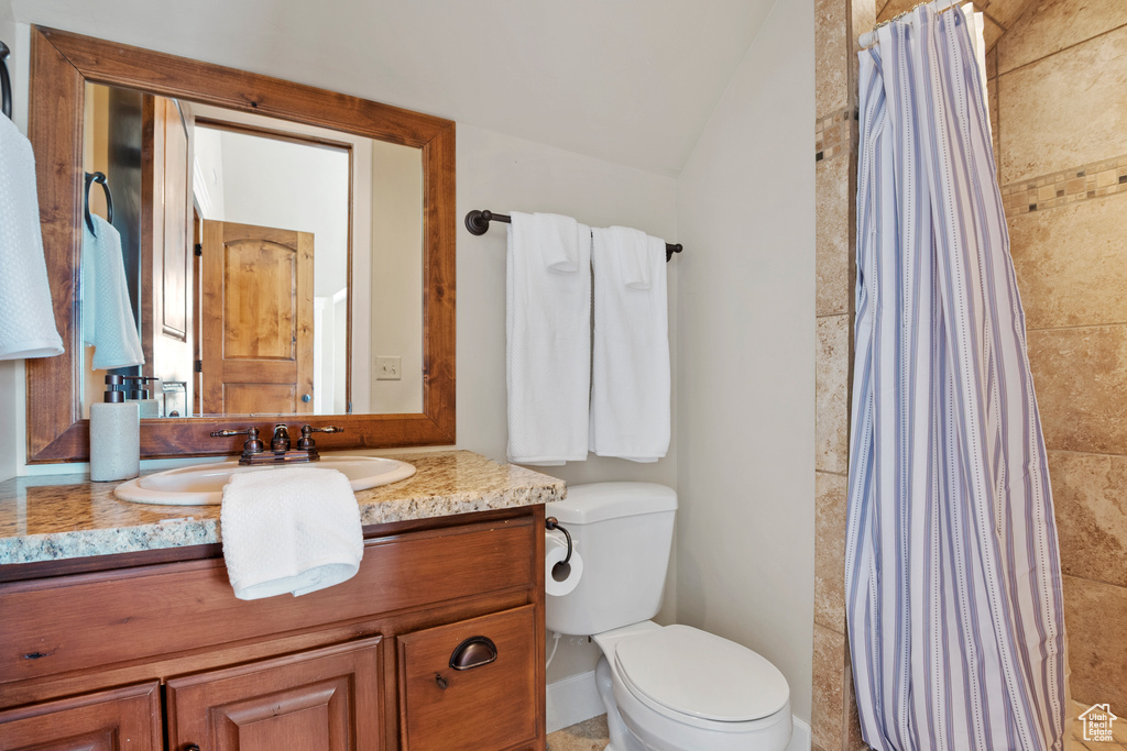 Full bath with vanity, lofted ceiling, and tiled shower