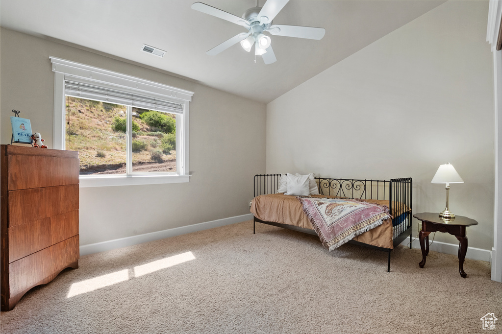Carpeted bedroom featuring vaulted ceiling and a ceiling fan