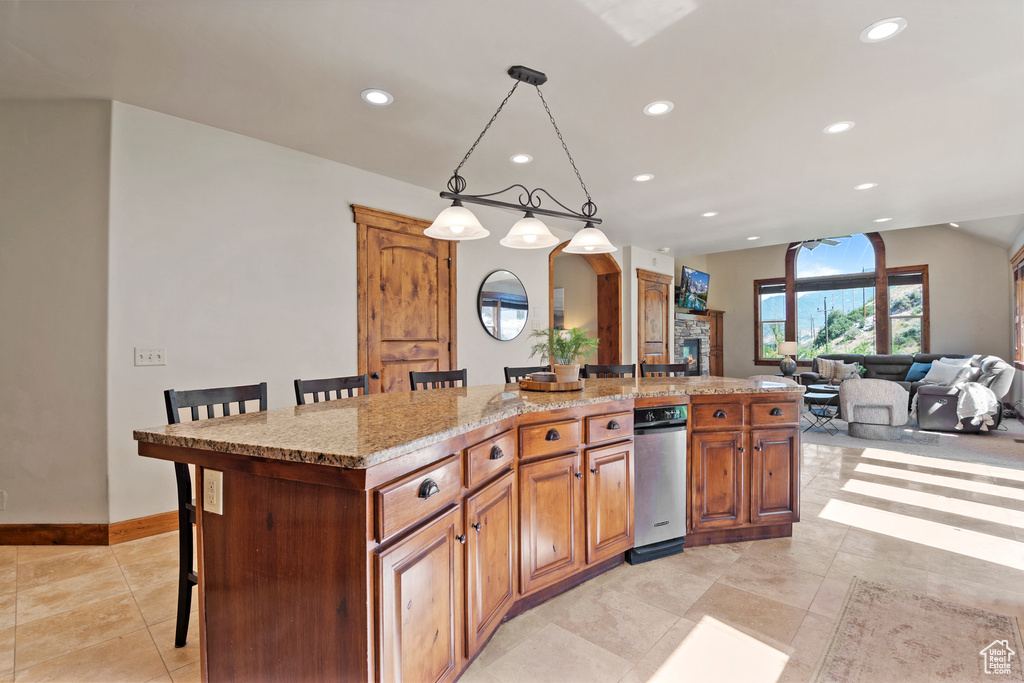 Kitchen with recessed lighting, a kitchen breakfast bar, a kitchen island with sink, light tile patterned floors, and pendant lighting
