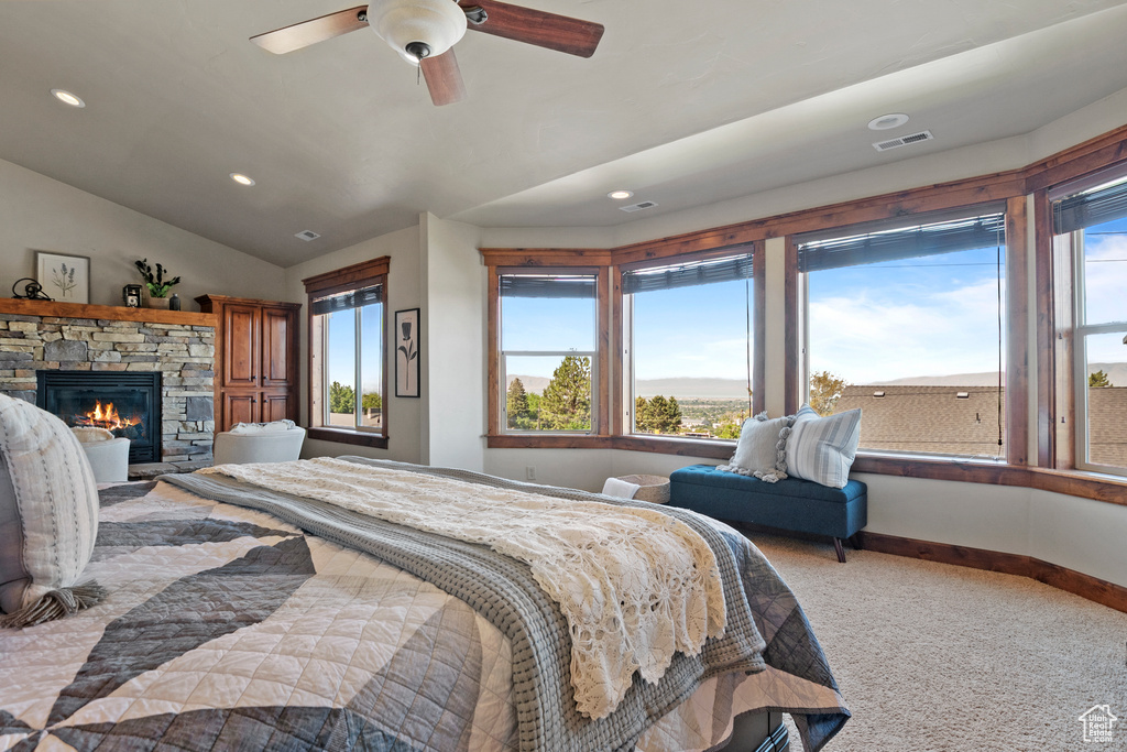 Bedroom featuring carpet flooring, a stone fireplace, lofted ceiling, recessed lighting, and a ceiling fan
