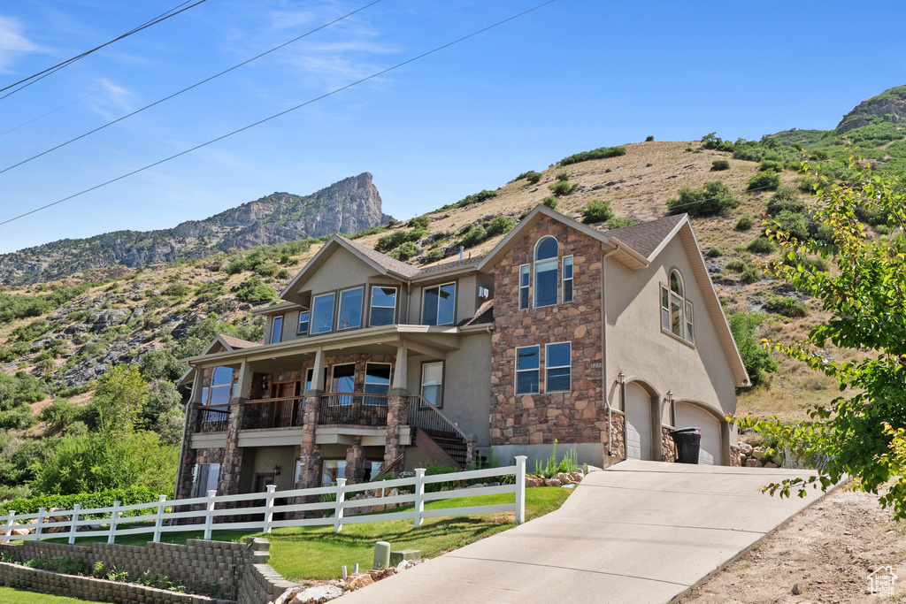 View of front of property with stone siding, stucco siding, a garage, concrete driveway, and a mountain view