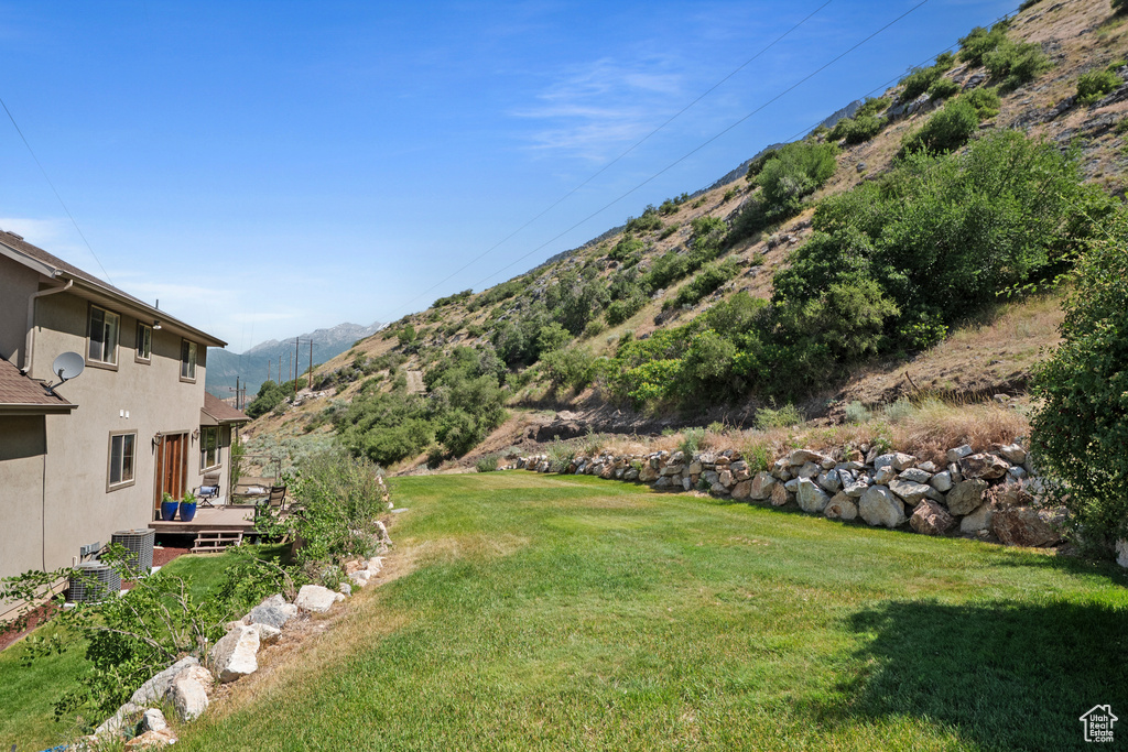View of grassy yard featuring a deck with mountain view