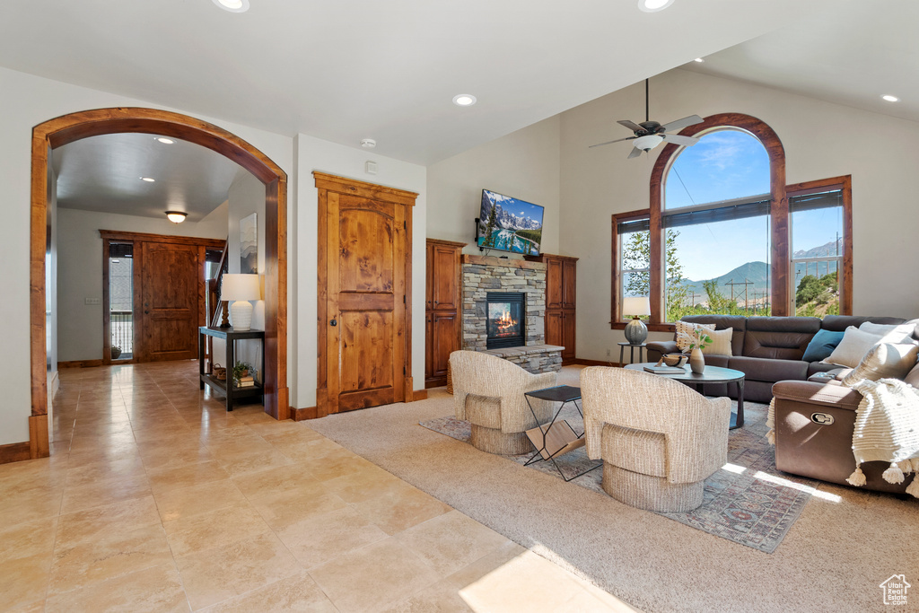 Living room featuring arched walkways, a fireplace, recessed lighting, a ceiling fan, and high vaulted ceiling