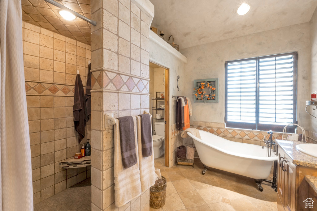 Full bathroom with tile walls, tile patterned floors, a soaking tub, a tile shower, and vanity
