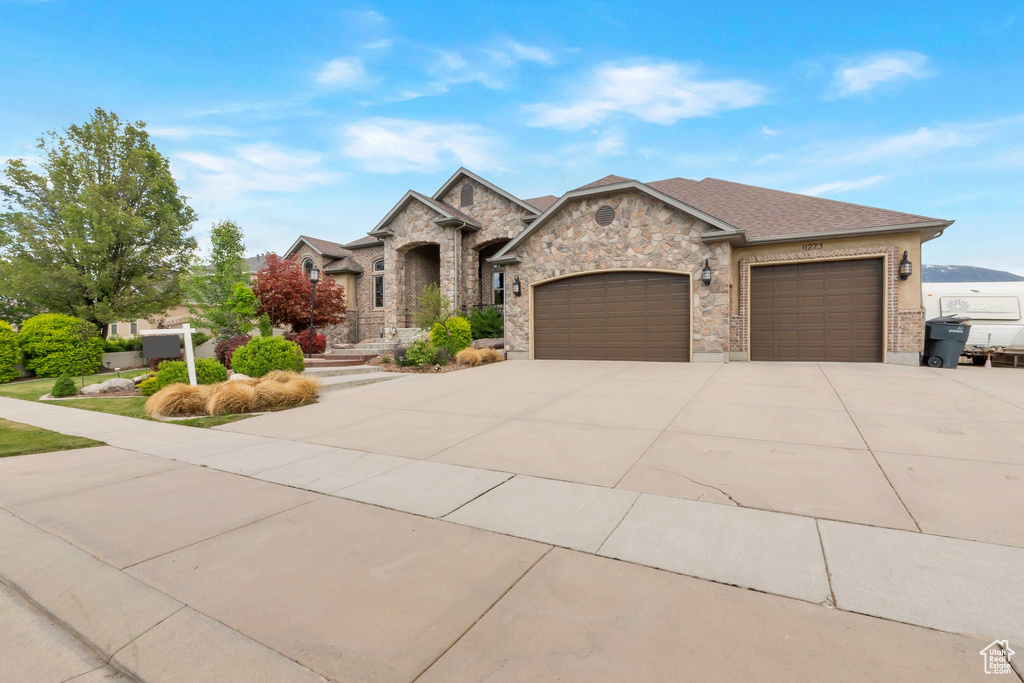 French provincial home with a garage, concrete driveway, and stone siding