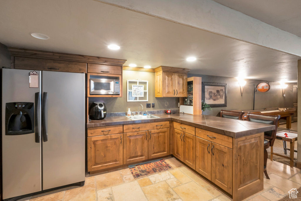 Kitchen featuring stainless steel refrigerator with ice dispenser, built in microwave, a peninsula, recessed lighting, and brown cabinets